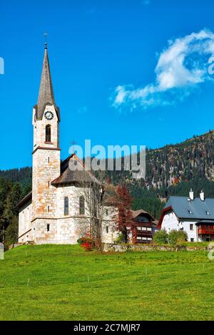 Montagne sopra il villaggio di Gosau con la Chiesa cattolica sotto la luce del sole. Località: villaggio turistico Gosau Salzkammergut regione, Valle di Gosau, alta Austria, Foto Stock