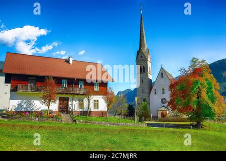 Montagne sopra il villaggio di Gosau con la Chiesa cattolica sotto la luce del sole. Località: villaggio turistico Gosau Salzkammergut regione, Valle di Gosau, alta Austria, Foto Stock