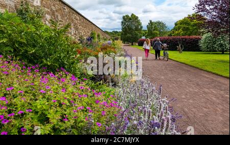 Due donne camminano sul sentiero passando il colorato confine dei fiori erbacei, Amisfield Walled Garden, Haddington, East Lothian, Scozia, Regno Unito Foto Stock