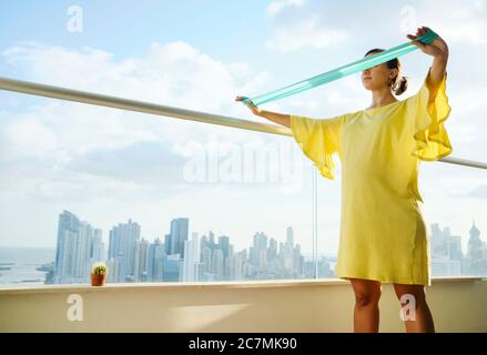 Donna incinta che si esercita con la fascia di gomma a casa Foto Stock