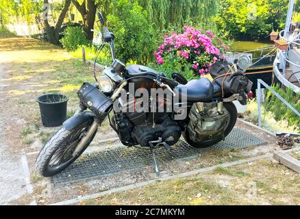 Liegi, BELGIO - 30 maggio 2020: Motocicletta Harley Davidson parcheggiata di fronte alla barca del proprietario vicino ad un fiume a Liegi, Belgio Foto Stock