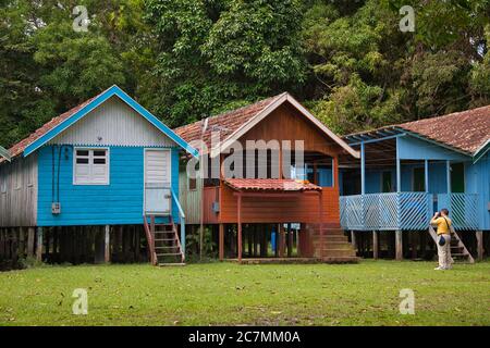 Tre rifugi di villaggio su palafitte per quando il fiume Amazzonia inonda, con il visitatore che scatta una fotografia, vicino Manaus nello stato di Amazonas, Brasile Foto Stock