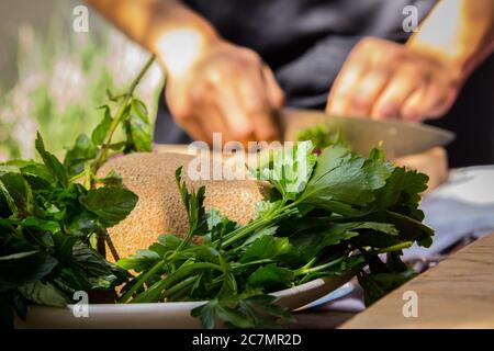 Primo piano di prezzemolo e tritare lo chef sullo sfondo Foto Stock