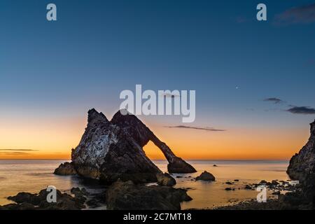 ARCO VIOLINO ROCCIA PORTKNOCKIE MORAY COSTA SCOZIA ESTATE MATTINA ALBA CON LUNA CRESCENT IN DECLINO E STELLA LUMINOSA IL PIANETA VENERE Foto Stock