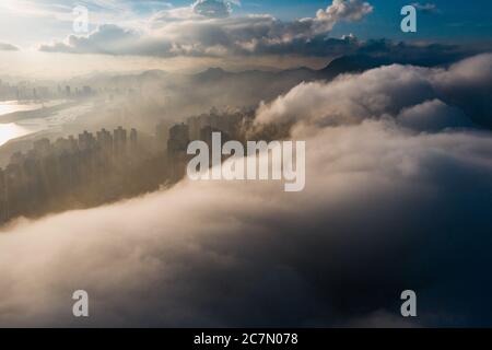 Affascinante scatto aereo del paesaggio urbano circondato dal verde sotto un cielo nuvoloso Foto Stock