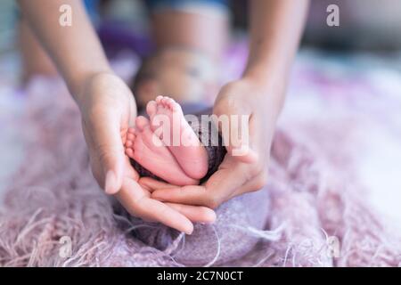 I piedini del bambino sono appoggiati alle mani Foto Stock