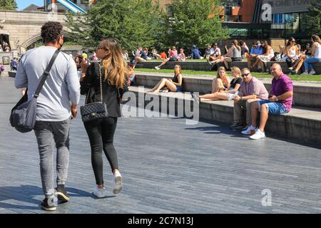 Londra, Regno Unito. 18 luglio 2020. Oggi, la gente cammina e si siede al sole nella zona intorno al municipio e al Potters Field Park. Il centro di Londra sembrava diventare più affollato oggi con più persone che lasciano le loro case per godersi il tempo soleggiato. Le regole di allontanamento sociale sembravano essere rispettate nella maggior parte dei luoghi, ma alcune aree sono già sempre affollate. Credit: Imageplotter/Alamy Live News Foto Stock