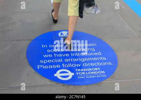 Londra, Regno Unito. 18 luglio 2020. Una donna attraversa un cartello sul London Bridge ricordando alle persone le regole di allontanamento sociale. Il centro di Londra sembrava diventare più affollato oggi con più persone che lasciano le loro case per godersi il tempo soleggiato. Le regole di allontanamento sociale sembravano essere rispettate nella maggior parte dei luoghi, ma alcune aree sono già sempre affollate. Credit: Imageplotter/Alamy Live News Foto Stock