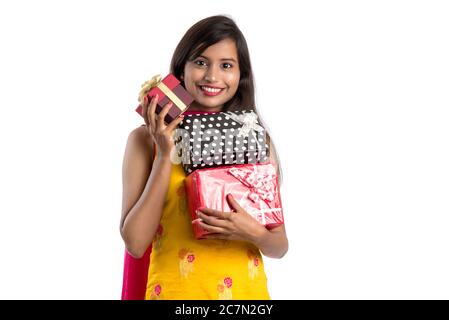 Ritratto di giovane ragazza indiana sorridente felice che tiene scatole regalo su uno sfondo bianco. Foto Stock