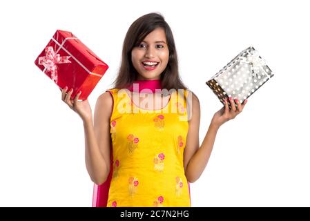 Ritratto di giovane ragazza indiana sorridente felice che tiene scatole regalo su uno sfondo bianco. Foto Stock