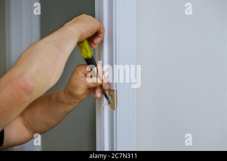Falegname lavoro con scalpello con foro porta in legno una serratura sta installando le porte Foto Stock