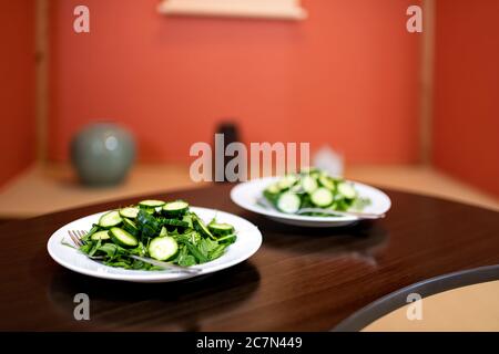 Tavolo di legno e pasto con insalata verde con cetrioli giapponesi e verdure di mizuna all'interno della casa in hotel ryokan o camera domestica con a tradizionale Foto Stock