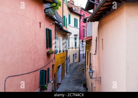 Vista ad alto angolo su chiusi, strada Italia vicolo stretto in piccolo villaggio storico in Toscana in serata con edifici multicolore rosa e OR Foto Stock