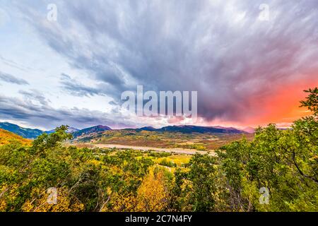 Aspen, Colorado Montagne rocciose colorato tramonto arancio rosso luce in cielo nuvole grandangolo alto vista aerea con tempesta nuvole e primo piano di p Foto Stock
