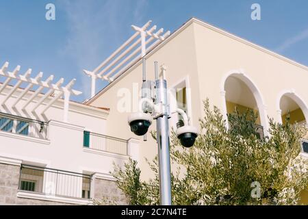 Telecamere di sorveglianza a cupola nere radiocomandate su palo, sullo sfondo dell'edificio. Foto Stock