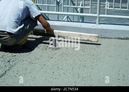 operatore manuale che lavora su calcestruzzo liscio su strada Foto Stock