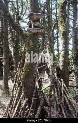 Un forte per bambini fatto di bastoni sotto un albero con i segni che leggono 'Ghosts of Yachats' a Yachats, Oregon, USA. Foto Stock