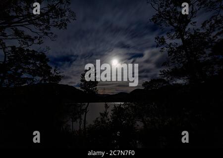 Un'immagine della luna che si infranaglia attraverso le nuvole sopra Ullswater nel distretto del lago Foto Stock