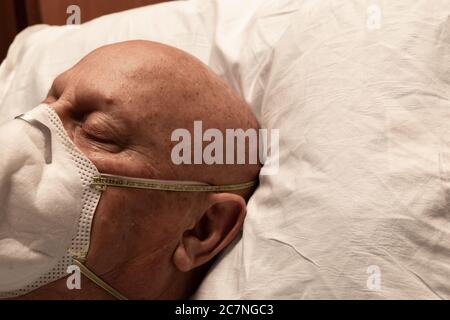 Capo di un uomo che indossa un respiratore, addormentato sulla zampa dell'ospedale, coronavirus chemioterapia calvo, spazio creativo di copia, aspetto orizzontale Foto Stock