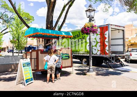 Taos, USA - 20 giugno 2019: Stand di cibo colorato nel centro di plaza piazza nel famoso villaggio della città con camion biologico e la gente che compra succhi Foto Stock