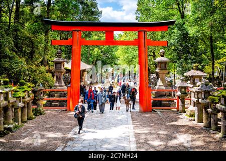 Nara, Giappone - 15 aprile 2019: Persone turisti stranieri folla molti camminare per l'ingresso Kasuga jinja torii cancello tempio santuario con percorso e vermillion Foto Stock