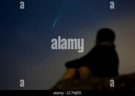 Una ragazza è vista guardare la Comet NEOWISE o C/2020 F3 dopo il tramonto con nuvole di fumo a causa dei forti incendi intorno alla città di Porto, Portogallo. Il 18 luglio 2020. La cometa è stata scoperta il 27 marzo 2020 da NEOWISE, il Near Earth Object Wide-Field Infrared Survey Explorer, che è un telescopio spaziale lanciato dalla NASA nel 2009. Foto Stock