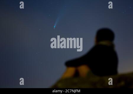 Una ragazza è vista guardare la Comet NEOWISE o C/2020 F3 dopo il tramonto con nuvole di fumo a causa dei forti incendi intorno alla città di Porto, Portogallo. Il 18 luglio 2020. La cometa è stata scoperta il 27 marzo 2020 da NEOWISE, il Near Earth Object Wide-Field Infrared Survey Explorer, che è un telescopio spaziale lanciato dalla NASA nel 2009. Foto Stock