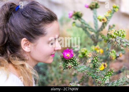 Giovane ragazza felice donna lato profilo odorante cane Cholla cactus fiore rosa sul Main Loop Trail nel Bandelier National Monument in New Mexico a Los Ala Foto Stock