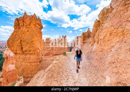 Donna che cammina sulle formazioni rocciose arancioni al Queens Garden Navajo Loop Trail al Bryce Canyon National Park nello Utah con una fotocamera felice sul sentiero Foto Stock