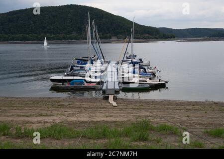 Edertal, Germania. 17 luglio 2020. Le barche a vela sono attaccate ad un molo nell'Edersee. Il livello dell'acqua dell'Edersee Nord Hessiano è sceso al di sotto del 50% e i primi resti di insediamenti abbandonati, i cosiddetti 'Edersee-Atlantis', sono già comparsi. Credit: Swen Pförtner/dpa/Alamy Live News Foto Stock