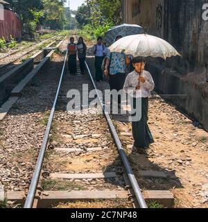 Un ragazzo ha un ombrello mentre cammina lungo la pista circolare di Yangon a Yangon, Myanmar Foto Stock
