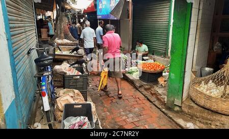 Vicolo stretto all'interno di un mercato cittadino locale con venditori Verdure e clienti in un bazaar a Kolkata India Foto Stock