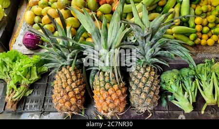 Negozio di frutta con ananas e manga in esposizione per la vendita in un mercato cittadino locale Foto Stock