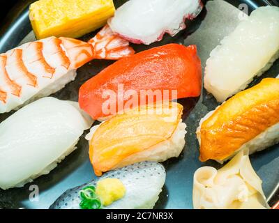 Inquadratura ad alto angolo di diversi tipi di sushi una piastra nera Foto Stock