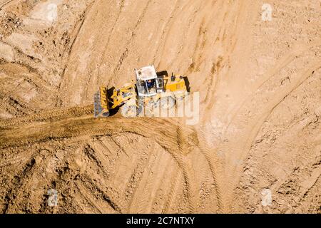 pala gommata gialla in cantiere, livellamento del terreno, spostamento e spianatura del terreno. immagine drone aerea Foto Stock