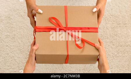 Le mani degli uomini danno una scatola con un regalo a a. donna Foto Stock