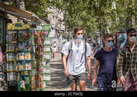 Barcellona, Spagna. 18 luglio 2020. Le persone che indossano maschere facciali sono viste passare accanto a uno dei chioschi che vendono semi e fiori sulla Rambla. La città di Barcellona affronta nuove epidemie di casi di coronavirus con nuove restrizioni di mobilità e raccomandazioni per evitare di viaggiare fuori città. Credit: SOPA Images Limited/Alamy Live News Foto Stock