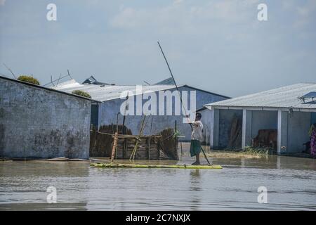 Bogura, Bangladesh. 16 luglio 2020. Un uomo guida una zattera di fortuna accanto alla sua casa allagata.almeno 1.5 milioni di persone sono state colpite, con case e strade in villaggi allagati. I funzionari del Centro di previsione e allarme delle inondazioni (FFWC) hanno riferito che la situazione delle inondazioni in 15 distretti centrali e settentrionali è stata dovuta all'aumento dei livelli d'acqua dei principali fiumi, tra cui Brahmaputra, Jamuna, Padma, Teesta e Dharla. Credit: SOPA Images Limited/Alamy Live News Foto Stock