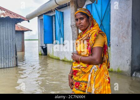 Bogura, Bangladesh. 16 luglio 2020. Una donna si pone di fronte alla sua casa allagata.almeno 1.5 milioni di persone sono state colpite, con case e strade in villaggi allagati. I funzionari del Centro di previsione e allarme delle inondazioni (FFWC) hanno riferito che la situazione delle inondazioni in 15 distretti centrali e settentrionali è stata dovuta all'aumento dei livelli d'acqua dei principali fiumi, tra cui Brahmaputra, Jamuna, Padma, Teesta e Dharla. Credit: SOPA Images Limited/Alamy Live News Foto Stock