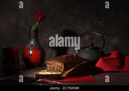 Pane da tè, vaso rosso e nero, rosa, teiera in ghisa nera e coltello Foto Stock