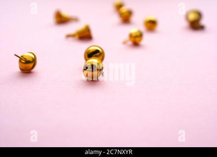 Piccole campane dorate su sfondo rosa, fuoco selettivo sul primo piano Foto Stock