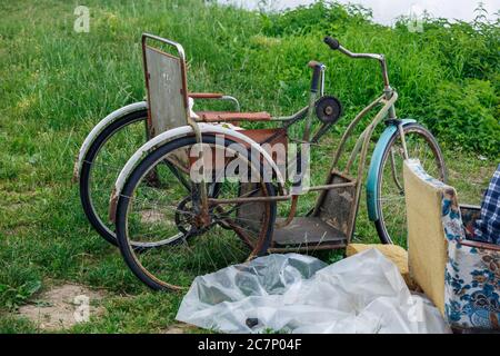 Città Plavinas, Lettonia. Vecchia bici arrugginita per disabili e erba verde sul fiume.18.07.2020 Foto Stock