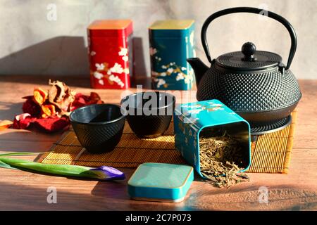 Teiera con foglie di tè verde sciolte con tazze e bambù mat Foto Stock