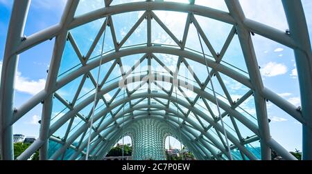 14 LUGLIO 2020, TBILISI, GEORGIA: Famoso ponte di vetro della Pace e Parco del Rike nella città vecchia di Tbilisi in giornata di sole con cielo blu luminoso Foto Stock