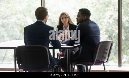 Tre imprenditori multietnici coinvolti in una conversazione durante la riunione di gruppo Foto Stock