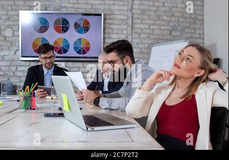 Giovane donna d'affari riuscita daydreaming circa il nuovo progetto emozionante di affari in un ufficio Foto Stock