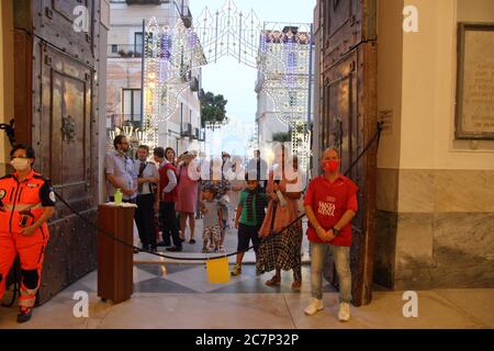 E fedeli che non potevano entrare hanno partecipato alla Santa Messa di fronte alla porta d'ingresso della Basilica di Santa Trofimena. Foto Stock