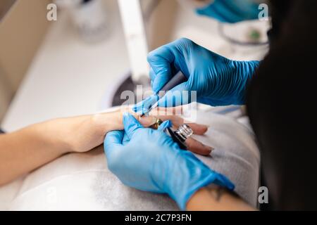 Il manicurista dipinge i chiodi con gel lucidante sui chiodi dei clienti. Foto Stock