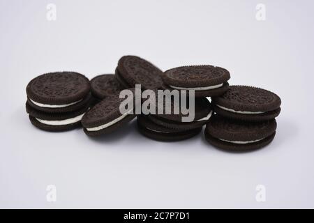 Biscotto nero al cioccolato con ripieno bianco, delizioso biscotto oreo al latte sparso su sfondo bianco. Foto Stock