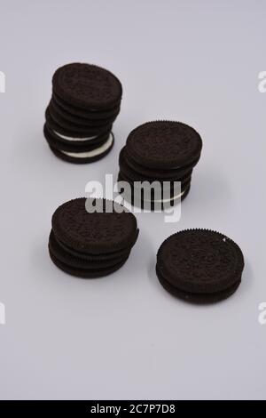 Biscotto nero al cioccolato con ripieno bianco, delizioso biscotto oreo al latte sparso su sfondo bianco. Foto Stock